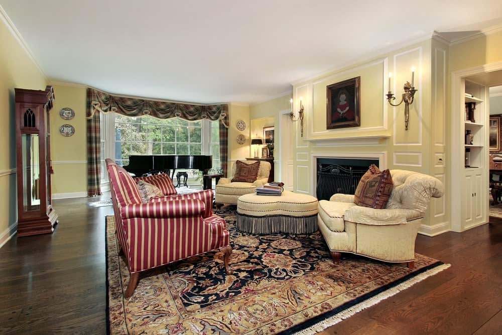 在这个黄色的客厅里，一张红色条纹沙发铺在流苏地毯上，显得格外显眼。客厅里有舒适的座椅和一幅装饰着一幅可爱画作的软凳，正对着壁炉。