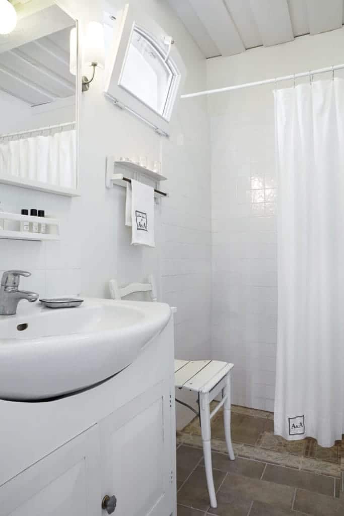 具体的瓷砖地板,与白色的墙壁和家具在这个时尚风格与基座水槽和一个小浴室淋浴区封闭环窗帘。