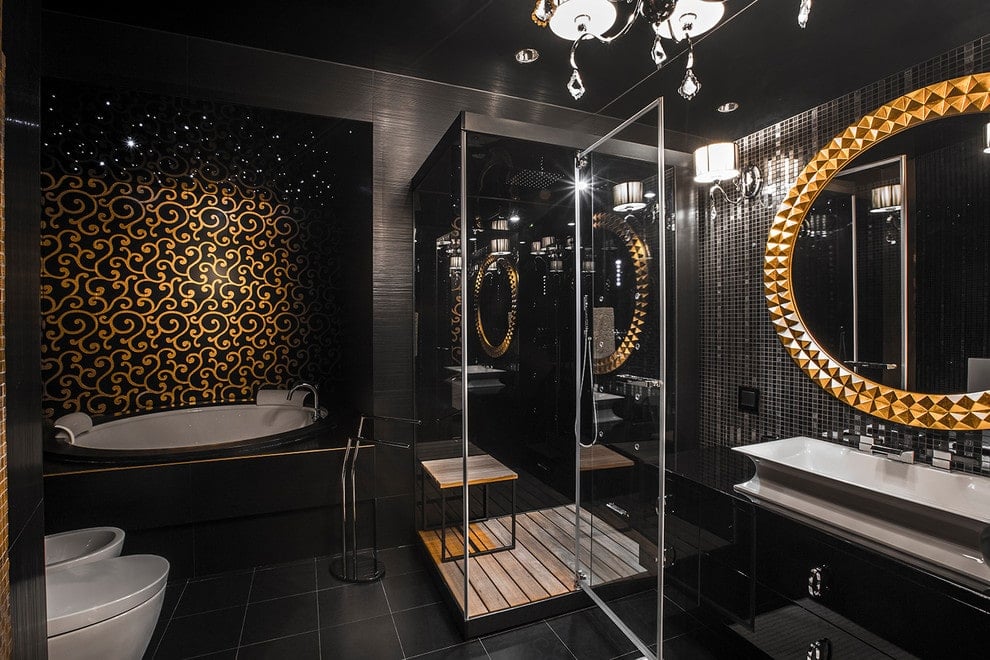 金色图案的墙壁为位于厕所旁边的深浴缸设置了一个优雅的背景。它伴随着一个步入式淋浴和一个高光泽的容器水槽梳妆台，带有一个华丽的圆镜子。