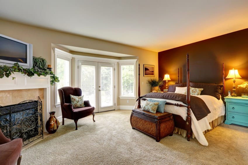 宽敞的主卧室设有棕色墙壁和地毯地板。房间的特色是一张舒适的床，两边都有台灯。房间里还有一座大壁炉。
