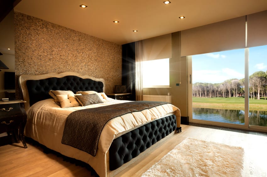 这间主卧室拥有一张豪华的床，配有华丽的小瓷砖墙和硬木地板。房间里有一扇滑动玻璃门，通往房子美丽的户外。