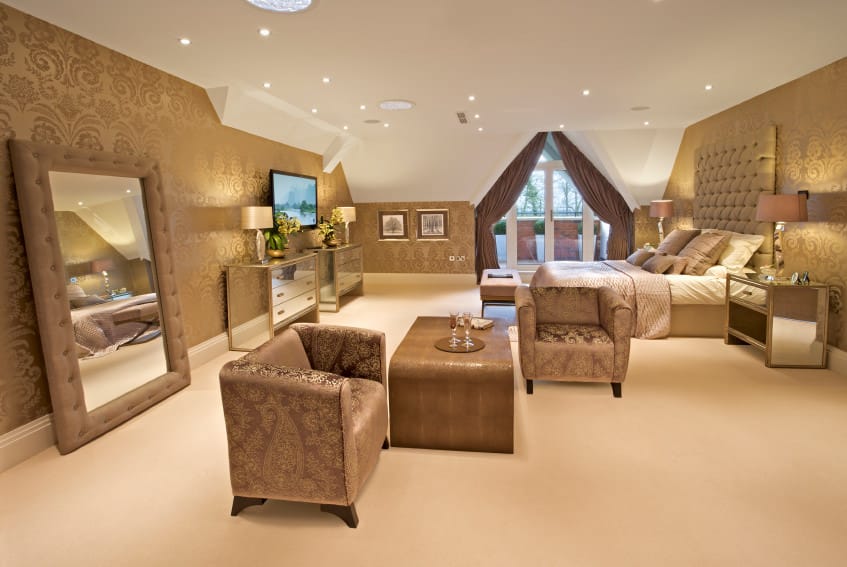 宽敞的主卧室拥有优雅的棕色墙壁和白色天花板。房间里有一张豪华的大床和一对优雅的棕色椅子。