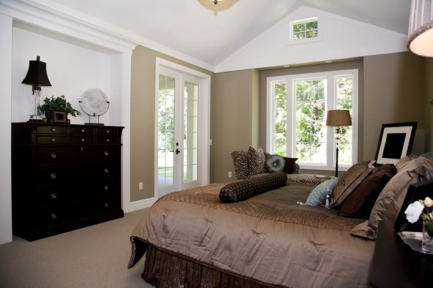 主卧室采用白色拱形天花板，铺有地毯的地板和棕色的墙壁。房间里有一张漂亮的棕色床。