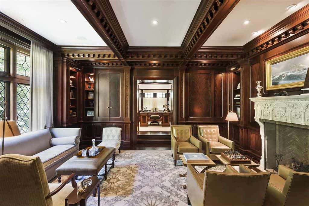 白色天花板的深色木质外露横梁有一种优雅的饰面，与这间美丽客厅的橱柜顶部的横梁相匹配。这为软垫沙发组提供了一个迷人的搭配，有图案的区域地毯覆盖了大部分的硬木地板。