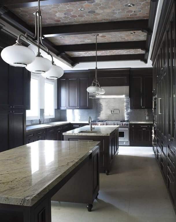 这间华丽的厨房天花板上装饰着户外六角形瓷砖，与裸露的深色木梁相得益彰。这与两个厨房岛和l形半岛的橱柜的深色色调相匹配。