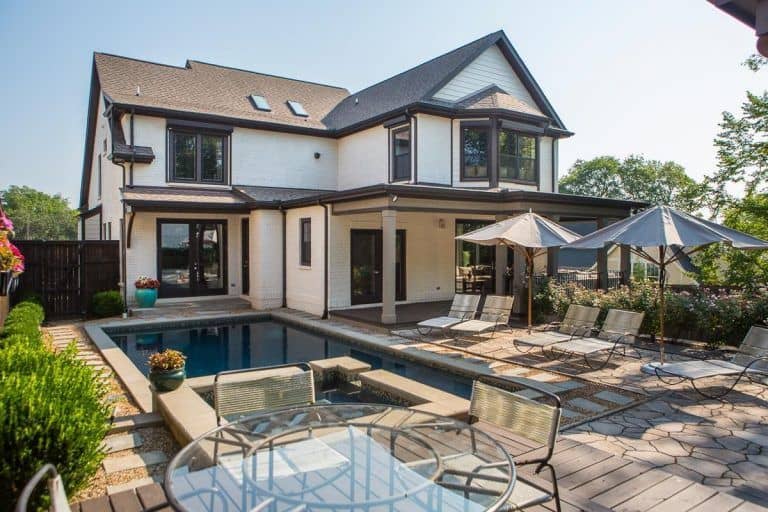 一个漂亮的房子，后院有游泳池和多个休息厅，还有一个户外餐桌。