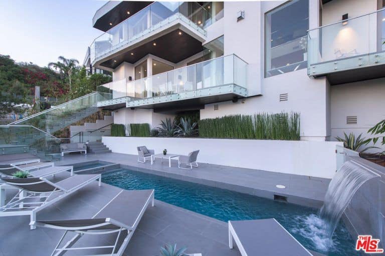 一座现代化的房子，有一个华丽的户外区域，设有一个时髦的游泳池，旁边有休闲座椅。