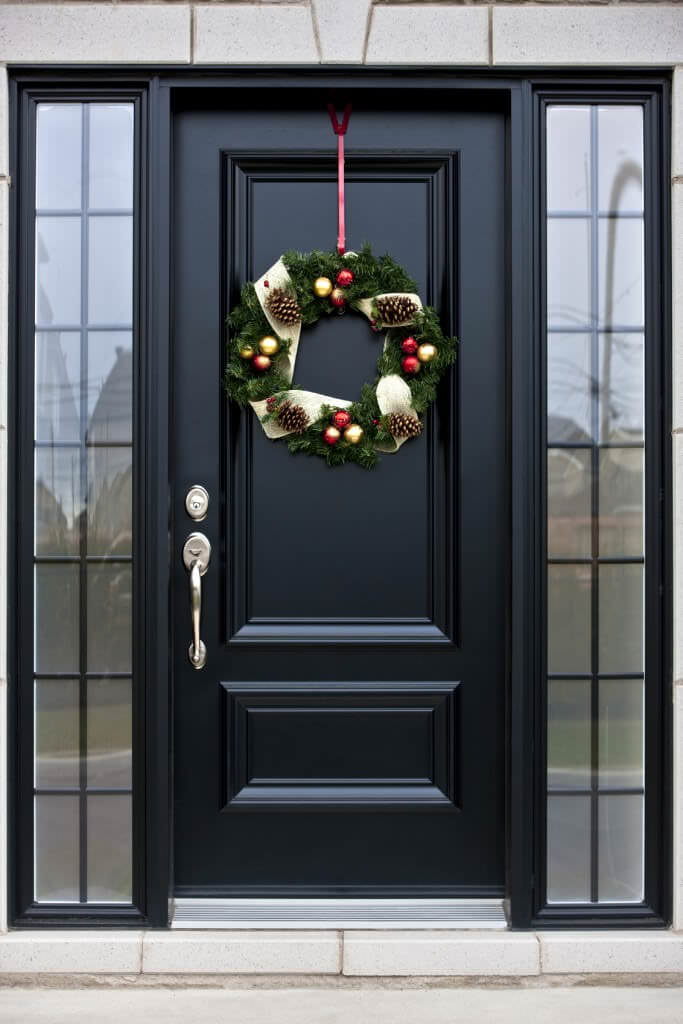 光滑的前门装饰着可爱的花环。它是由玻璃镶嵌在黑色铝框。