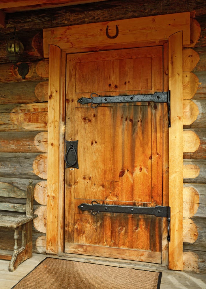 工匠前门，配有金属五金，壁灯和黄麻地毯。旁边有一张质朴的长凳，与大木梁融为一体。