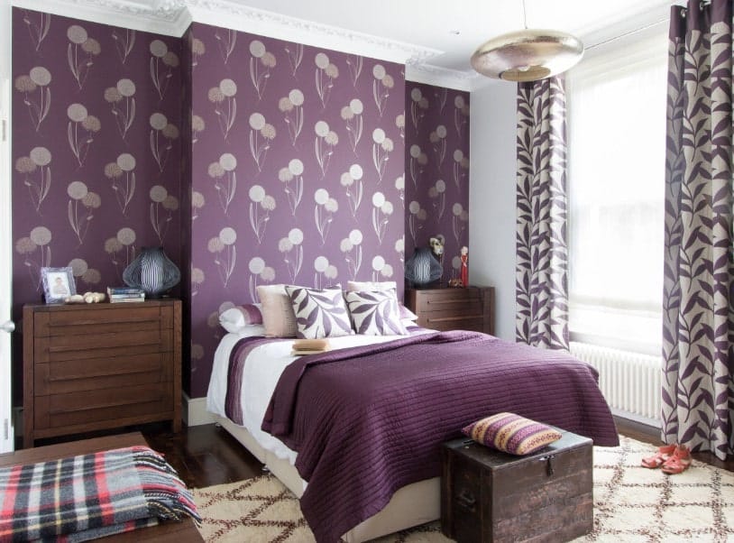 主卧室拥有时尚的紫色墙壁和优雅的白色天花板。房间提供一张舒适的床，两边都有床头柜。