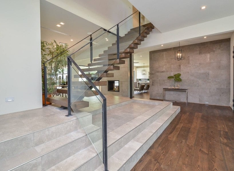 重点看这个家的现代楼梯与硬木台阶和玻璃栏杆。该住宅以硬木地板和时尚的墙壁为特色。