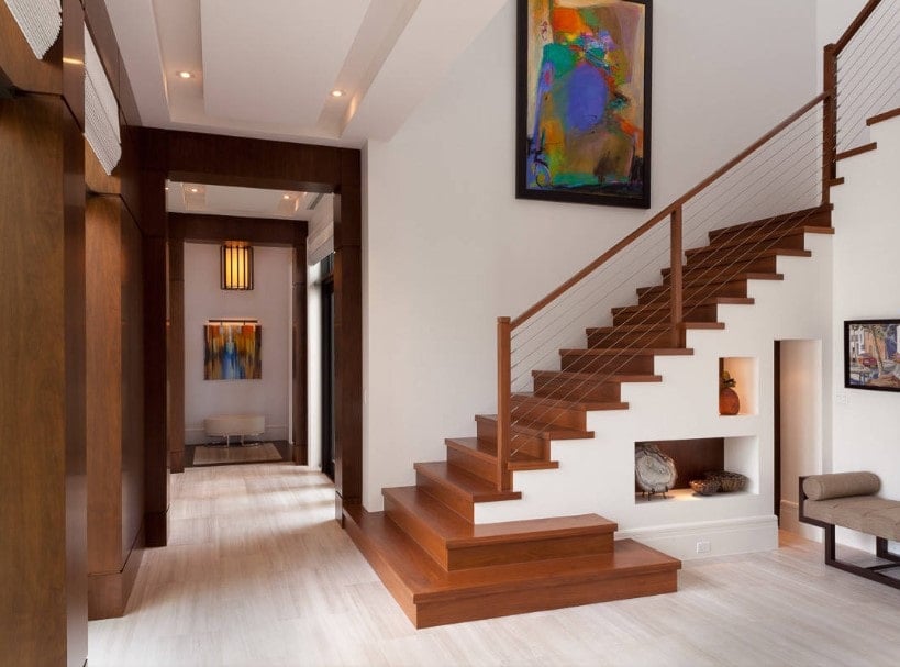一个现代的家庭，拥有华丽的楼梯，硬木台阶被家庭的白色墙壁包围，带有艺术墙壁装饰。