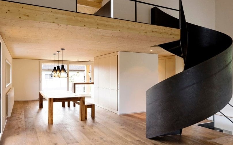 一座现代的房子，有木制天花板和硬木地板，还有一个令人惊叹的黑色螺旋楼梯。