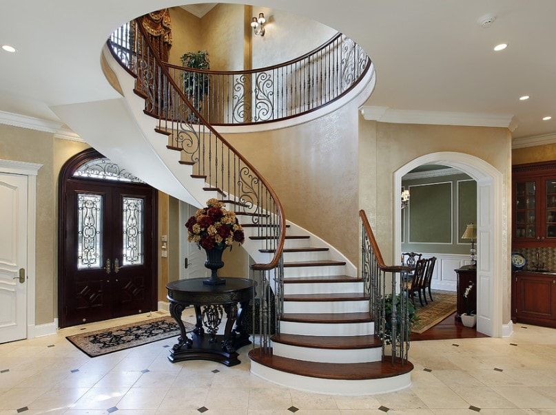 一个家庭的门厅拥有优雅的楼梯，以及优雅的瓷砖地板和米黄色的墙壁。