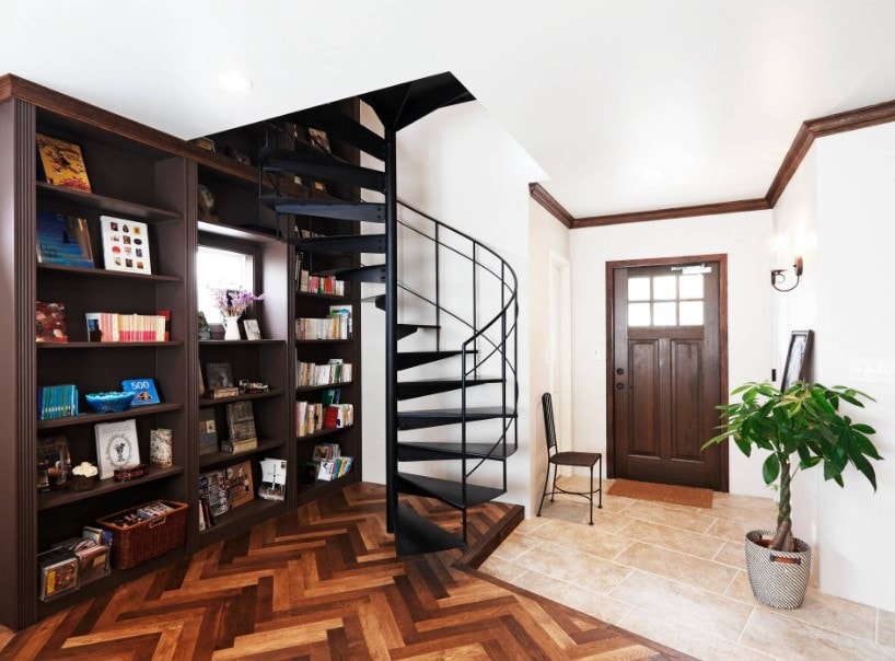 门厅有时尚的硬木地板和内置的多个书架，以及一个黑色的螺旋楼梯。
