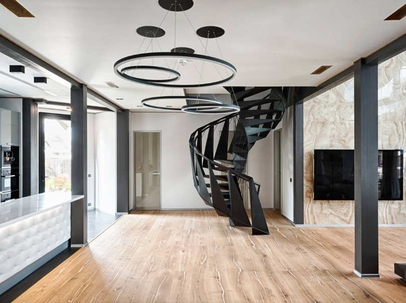 一个宽敞的大房间，有时尚的天花板和硬木地板，以及一个非常吸引人的黑色螺旋楼梯。