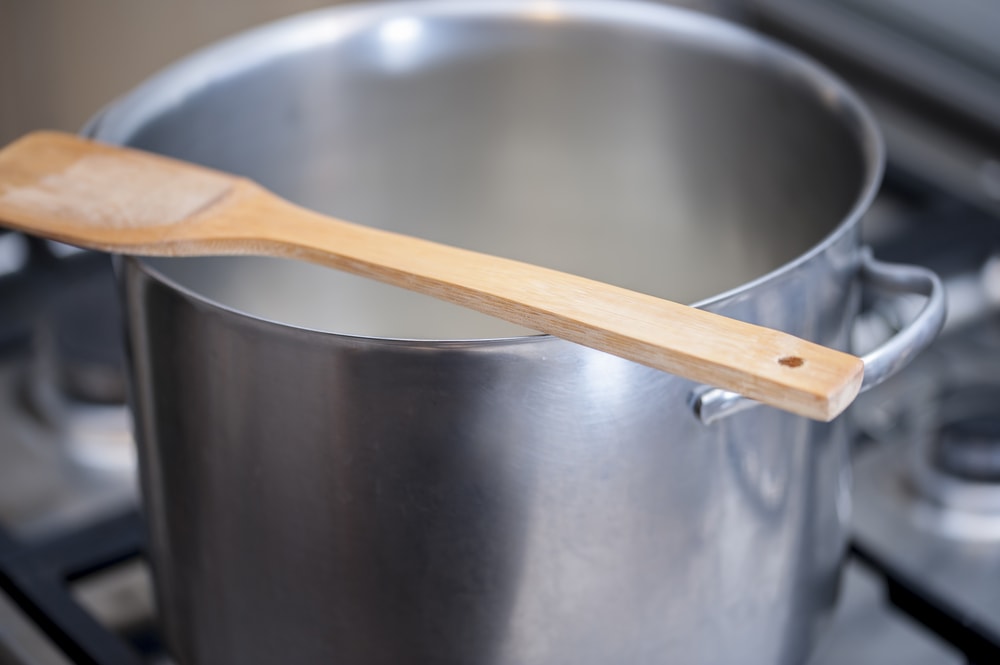厨房用的木制勺子放在开着的锅边。