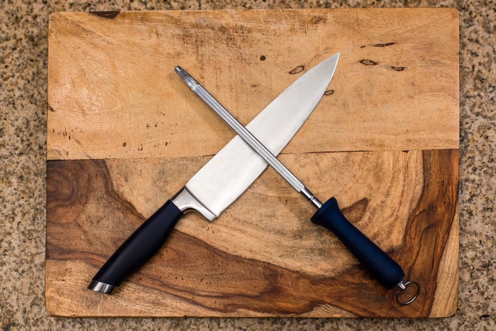 一把刀和一个磨刀器放在木砧板上。
