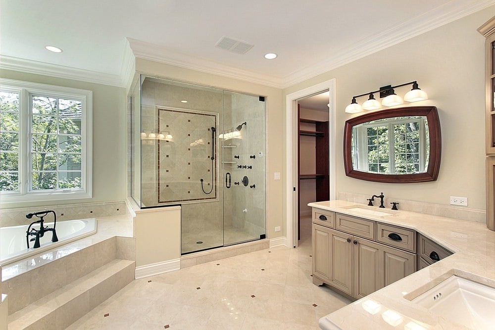 步入式淋浴间旁边有一个浴缸，配有锻铁装置。它配有一个带有双水槽和木框镜子的弯曲梳妆台。