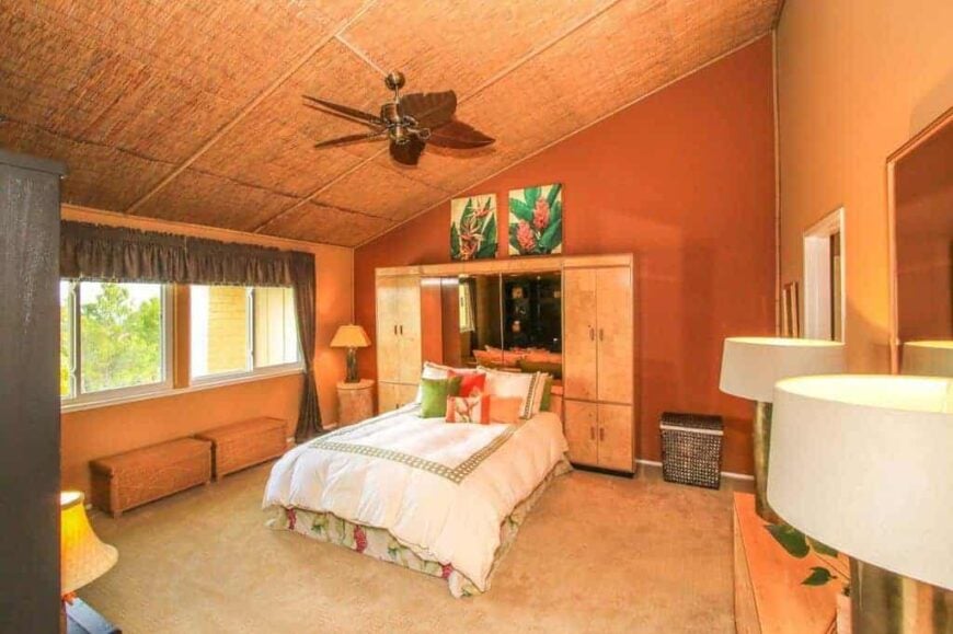 主卧室有橙色的墙壁和棚顶，还有地毯地板。房间提供一张双人床，两侧有两个衣柜。