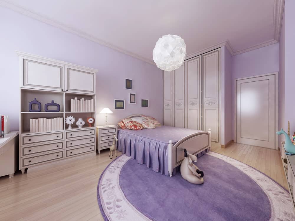 宽敞的主卧室配有华丽的紫色床和大圆形地毯。房间四周是紫色的墙。房间由迷人的顶灯照亮。