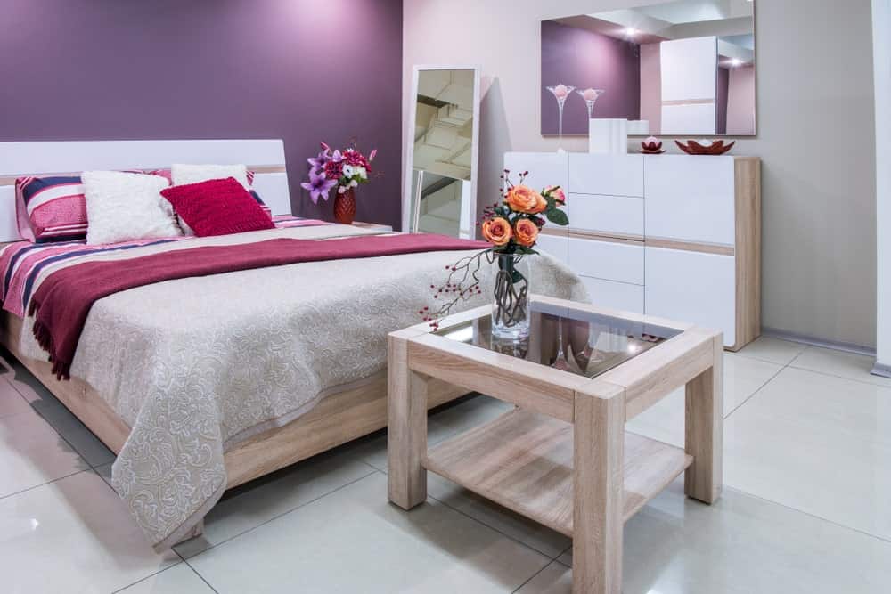 主卧室设有中等瓷砖地板和紫色墙壁，以及一张舒适的床。