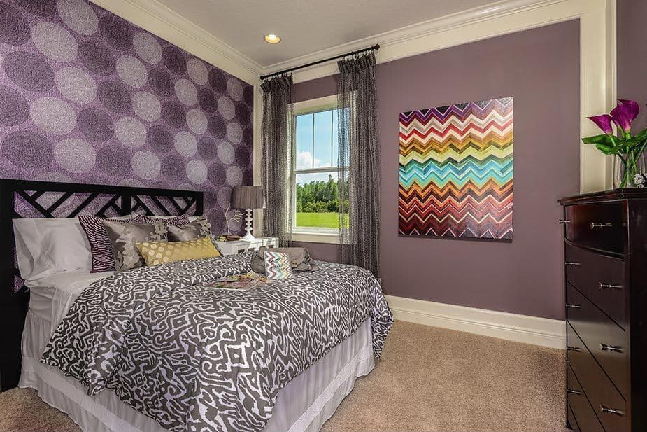 这间卧室提供一张舒适的床，周围环绕着时尚的紫色墙壁和地毯地板。
