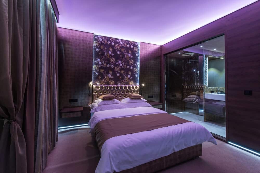 主卧室拥有时尚的床设置，周围环绕着时尚的紫色墙壁和紫色地毯地板。这个房间还有自己的现代风格的浴室。