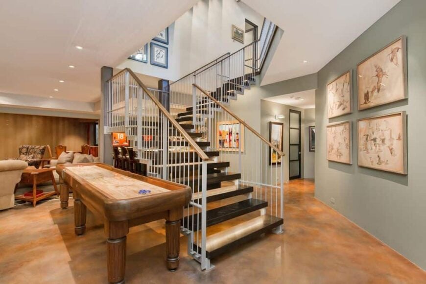 近距离看这个有时尚台阶和铁栏杆的四分之一转弯楼梯。该住宅以棕色瓷砖地板和浅灰色墙壁为特色，带有艺术风格的墙壁装饰。