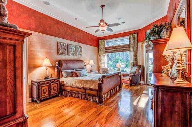 宽敞的主卧室以优雅设计的红墙环绕整个房间。这里有一张精致的床，有两个床头柜，上面有台灯。房间还设有硬木地板。