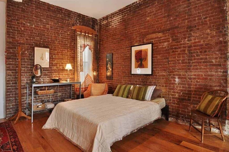 一间主卧室，有一张漂亮的床，四周是红砖墙。房间还设有硬木地板。