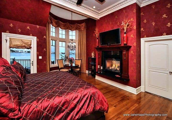 主卧有红色装饰的墙壁和优雅的红色天鹅绒床，前面有壁炉和电视机。房间设有靠窗的休息区和阳台区。