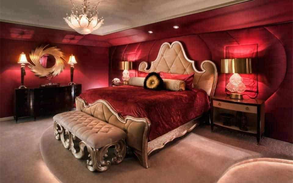 豪华的主卧室拥有一个优雅的主床，两边都有镀金的台灯。房间四周是红墙和地毯地板。