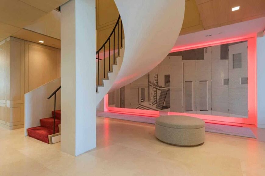 当代住宅拥有带有红地毯台阶的螺旋楼梯。这所房子还有一个带有粉红色照明的大型墙壁艺术。
