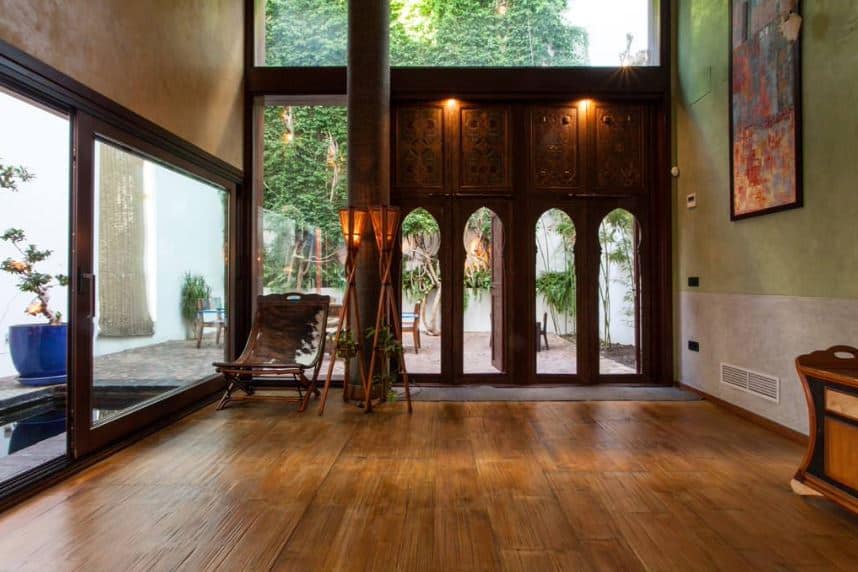 这个热带风格的门厅有一个独特的木制主入口，看起来像寺庙的入口。这与一个巨大的横梁玻璃窗和玻璃墙相平衡，玻璃墙上装饰着几个丛林手电筒和一个动物皮吊床椅。