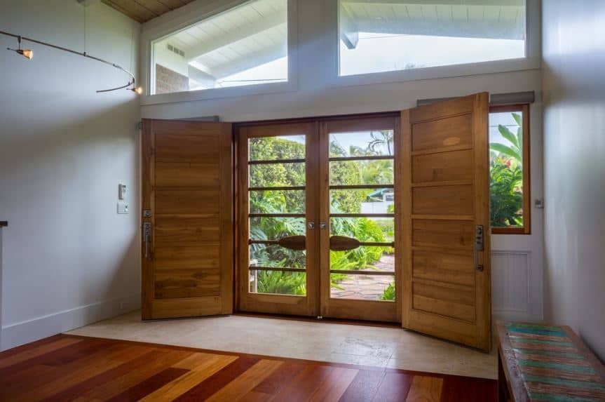 丰富的自然光通过大横梁窗和主门的玻璃板倾泻到这个门厅，主门的木框与一侧的木凳相匹配。这些框架看起来像桨，赋予门的特点。