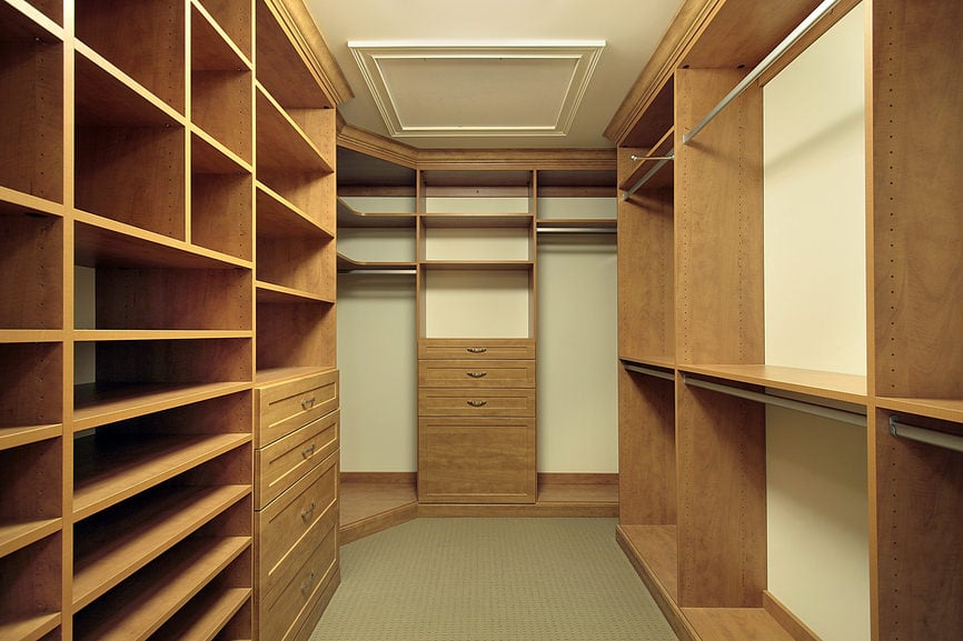 天然木橱柜贯穿整个步入式衣柜，灰褐色地毯地板和米黄色墙壁与常规天花板相匹配。