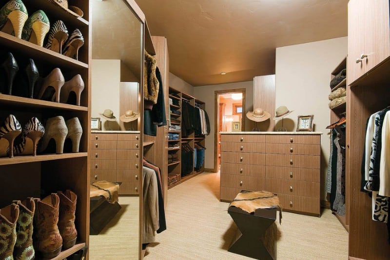 男女通用的步入式衣柜，开放式储物间和木制柜台，配有充足的抽屉。它是由一个棕色的长凳，上面有一个牛皮的扔。