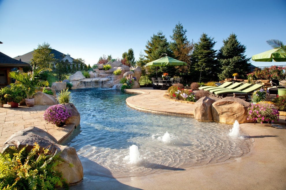 巨石瀑布和泳池起泡器是这个后院游泳池中的一些亮点，有多个座位和可爱的花朵在该地区带来了多种颜色。