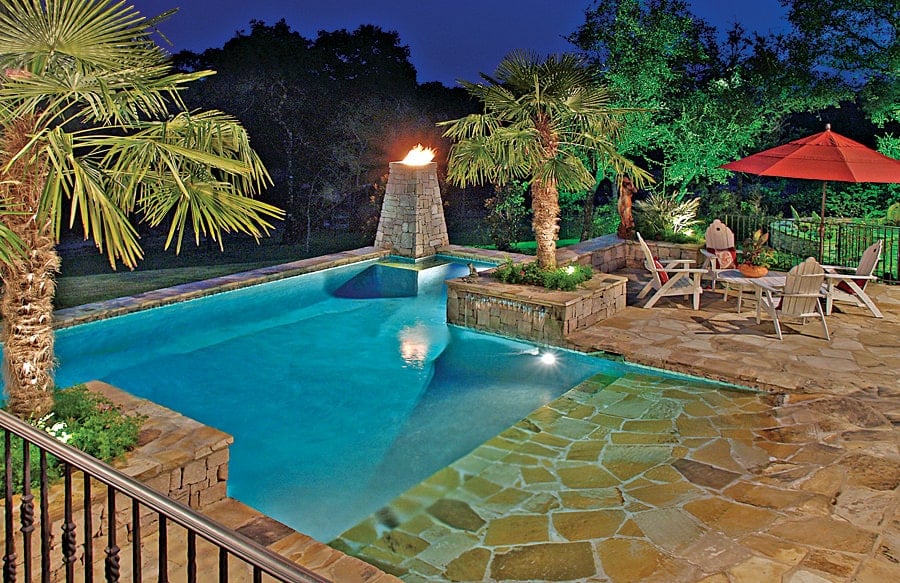 后院游泳池装有石板甲板，侧面装满了棕榈树。它包括一个座位区和晚上院子里加入院子的火炬。 