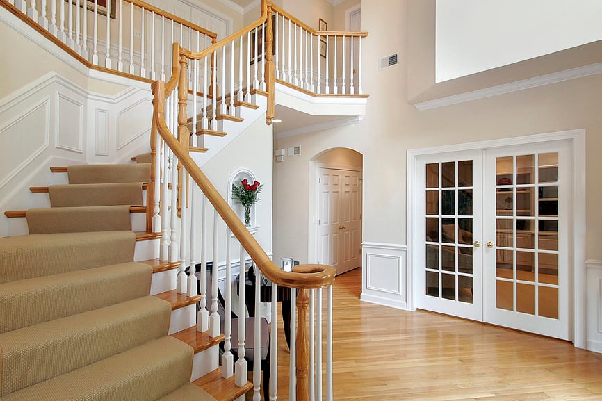 这座住宅的180度转弯硬木楼梯具有白色主轴栏杆，木扶手和地毯台阶。木质台阶与门厅的硬木地板相呼应，门厅的法式双开门通往一间书房。