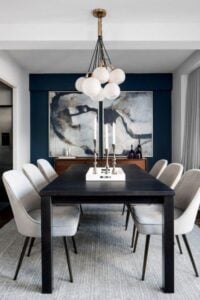 这个现代餐厅有完美的配件数量，使大胆和简单的声明。深蓝色的墙壁将你的注意力吸引到抽象艺术上，为这个房间带来“哇”。