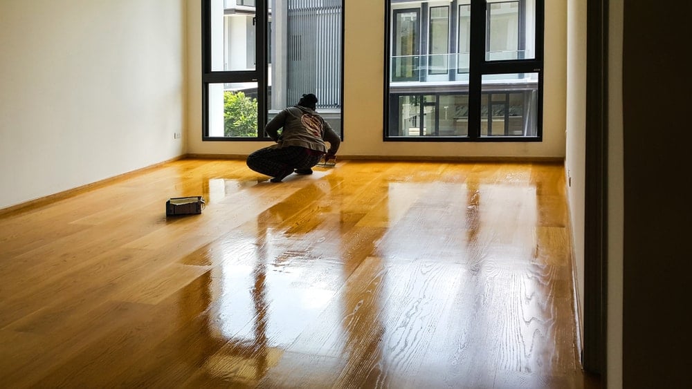 一名男子在工程木地板上涂聚氨酯涂料。