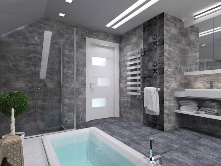 定制主浴室与惊人的灰色瓷砖地板和墙壁。它有一个漂亮的落地式浴缸和一个步入式淋浴区。