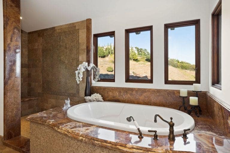 这张照片聚焦在一个大型定制平台上的主浴室的深浴缸。步入式淋浴区设置在浴缸旁边。