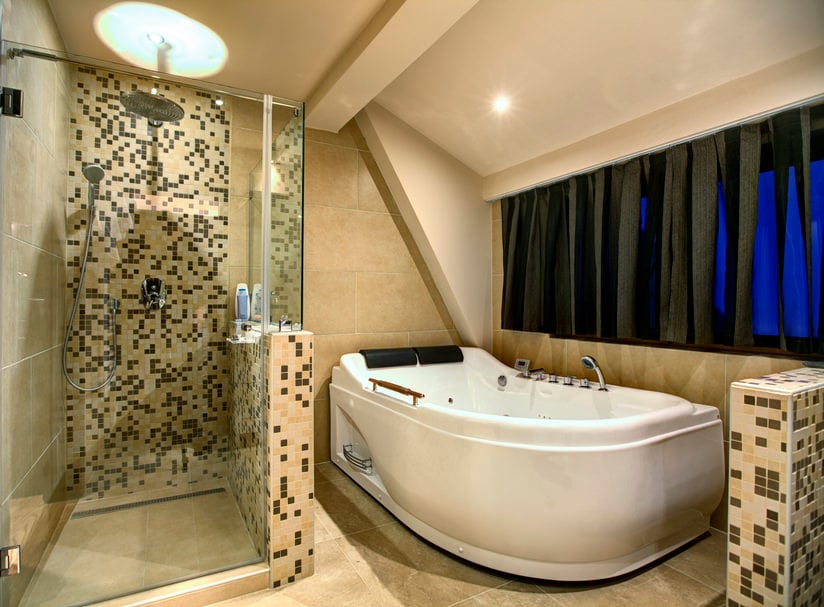 专注地看这个浴室的大型独立式深泡浴缸和一个带有时尚瓷砖墙壁的步入式淋浴房。