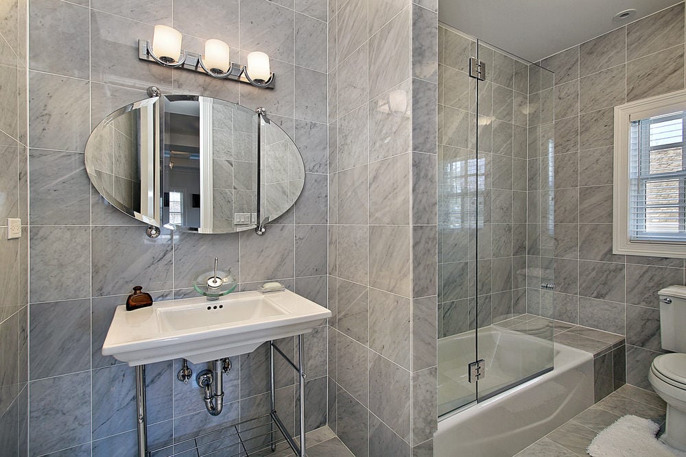 这间主浴室设有淋浴和浴缸组合，以及传统的厕所，并配有白色蓬松的地毯。它包括一个镀铬底座的水槽底座和一个由玻璃烛台照明的椭圆形镜子。