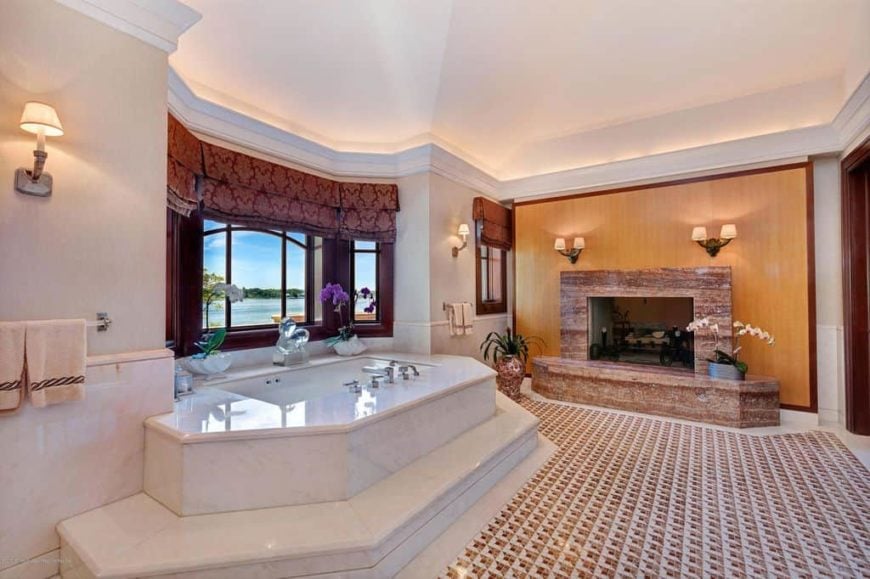这间主浴室拥有一个华丽的浸入式浴缸，位于瓷砖平台上，旁边还有一个大壁炉。房间设有时尚的瓷砖地板和美丽的天花板。