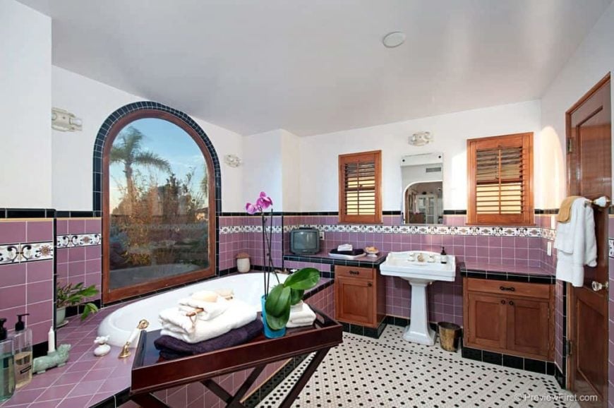 主浴室配有时尚瓷砖地板，紫色瓷砖墙壁和紫色瓷砖浴缸平台。这间浴室还有一个台式水池。