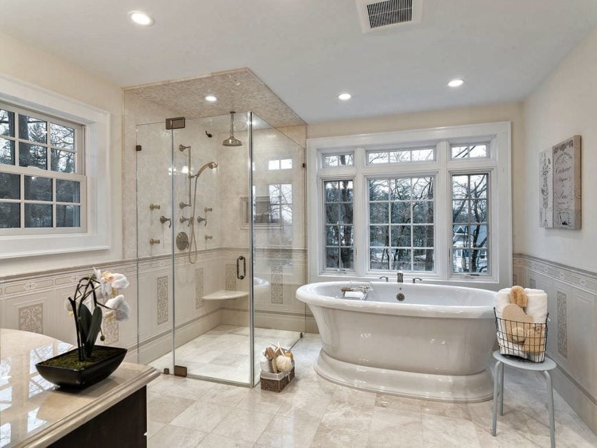 主浴室瓷砖地板和优雅独立浸泡浴缸、水槽一起对抗大理石台面和步行玻璃淋浴房。